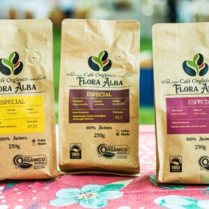 Home Close-up of organic coffee bags, Flora Alba brand, displayed on a table at an outdoor market.